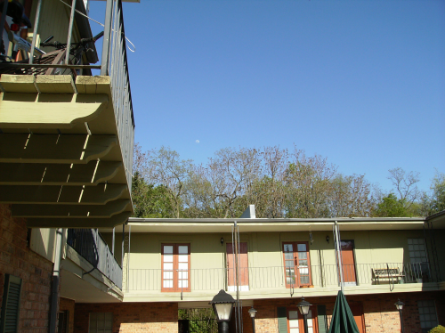 A look up at the second story apartments with the moon in the distance